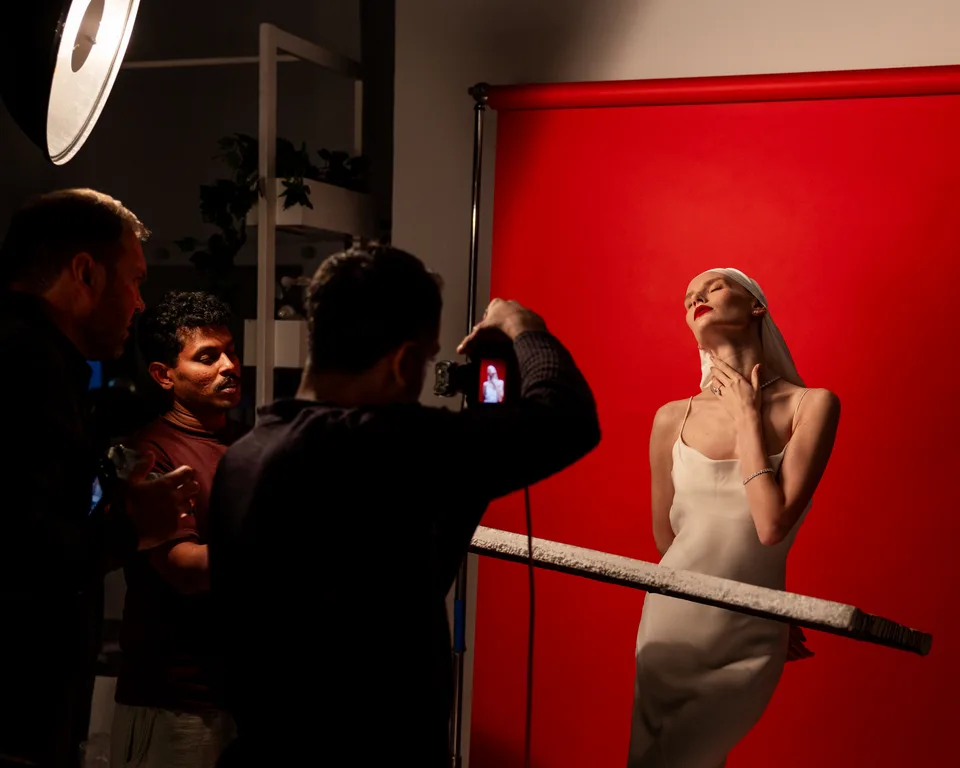 A photographer capturing the model against a red backdrop on the Magnurs campaign set